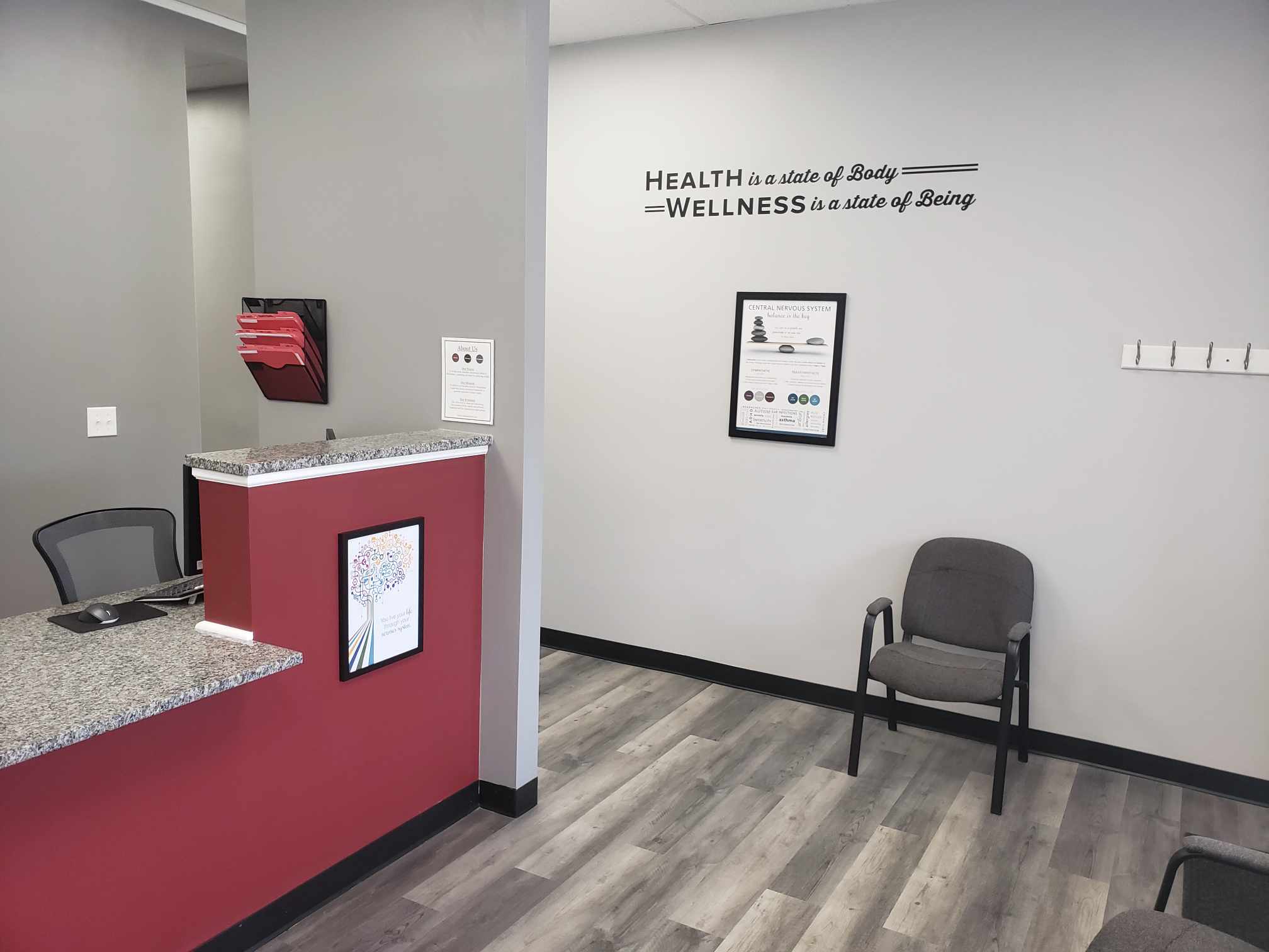 Reception area with a chair, wall lettering reading Health is a state of body, wellness is a state of being, and the front counter